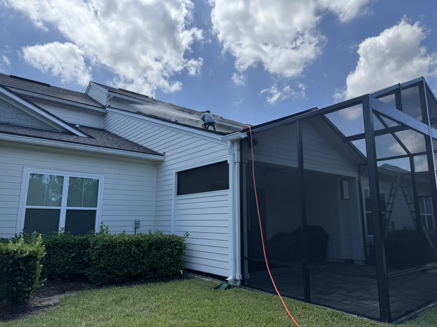 FCPE specialist reaching upper soffit on a soft-wash treatment in Northeast Florida