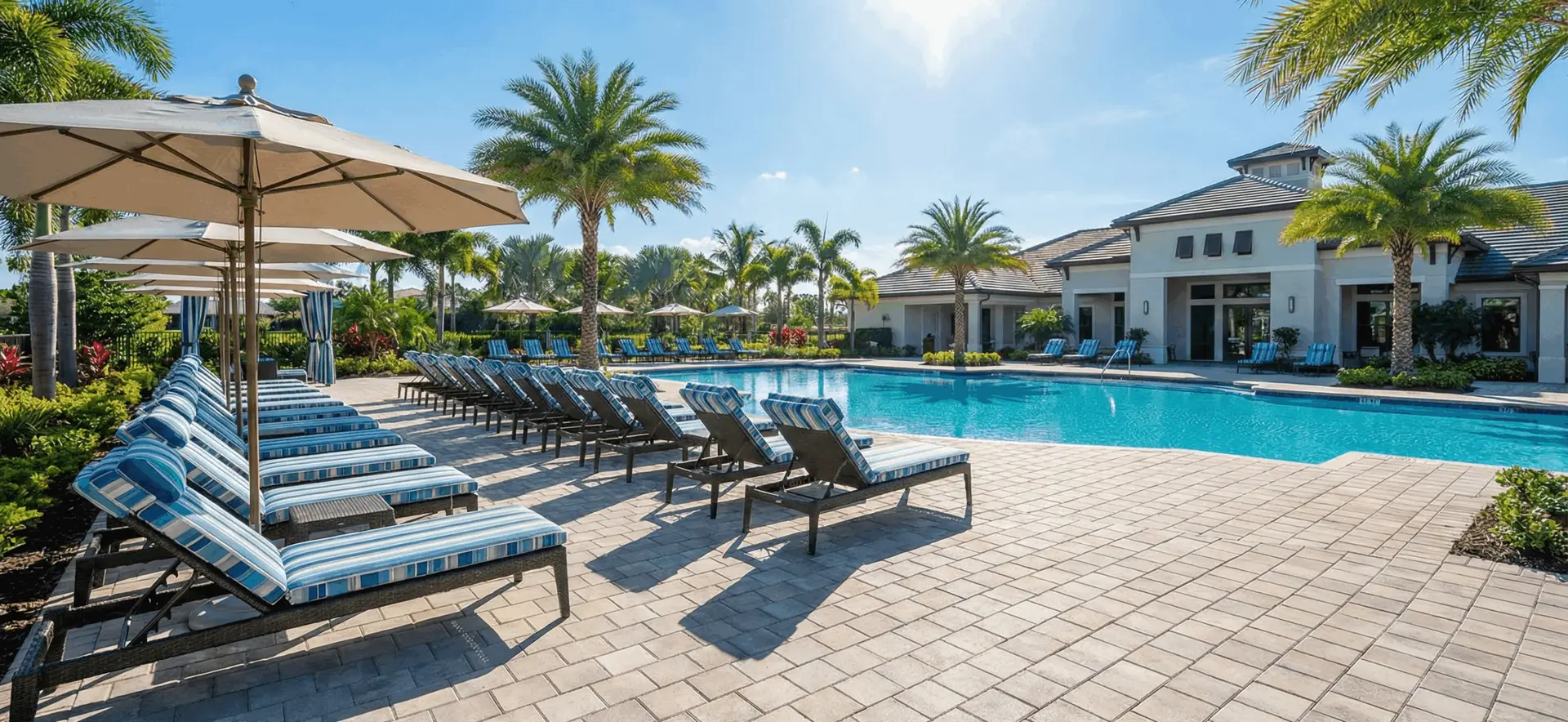 Pristine community pool deck with aligned lounge chairs and clean pavers