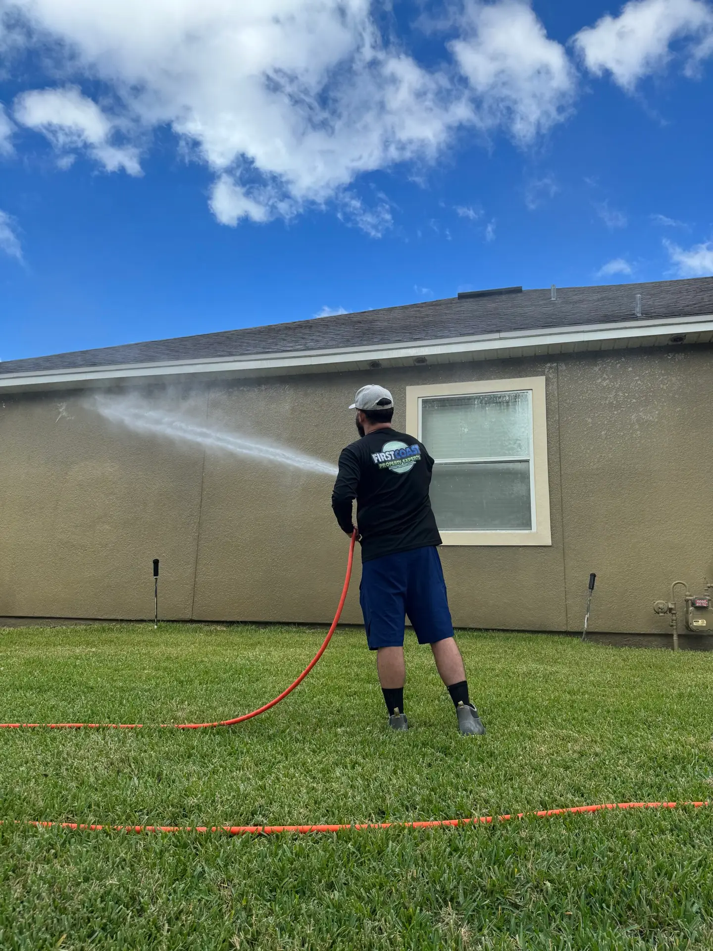 Luxury stucco home exterior being professionally soft washed to safely remove dirt, algae, and mildew in Northeast Florida